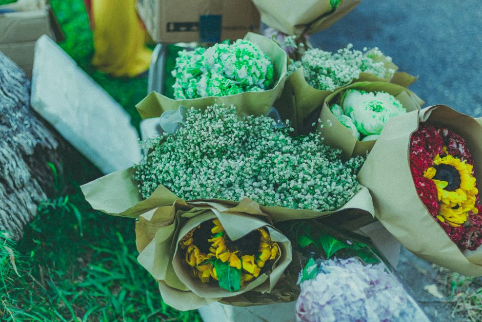 A collection of freshly arranged flower bouquets displayed on a surface, featuring a variety of blooms including white baby's breath, yellow sunflower-like flowers, and green-tipped hydrangeas. The fl